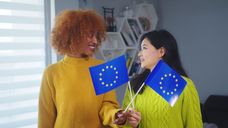 Multiracial friendship and equality, African american and asian woman holding european union flag.