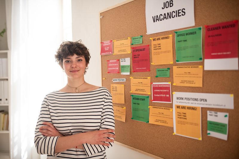 Young woman standing by job vacancies notice board