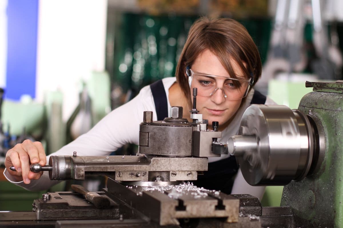 Young woman working the metal working lathe